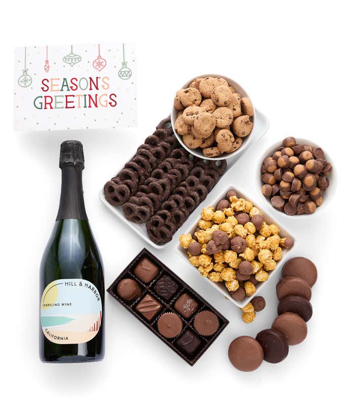 A gift set featuring a bottle of California Sparkling Wine paired with chocolate-covered pretzels, mini cookies, caramel popcorn, chocolate peanut butter buckeyes, 6 chocolate-covered Oreos, a box of assorted chocolates, and Season's Greetings card.