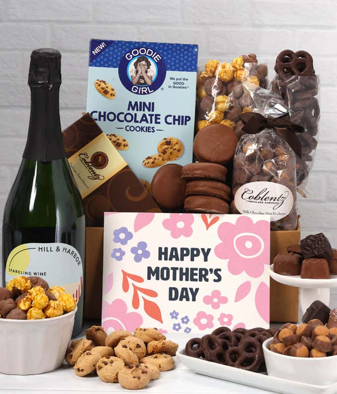 A bottle of Hill & Harbor Sparkling wine sits beside chocolate-covered pretzels, mini chocolate chip cookies, caramel popcorn, assorted chocolates, mini buckeyes, chocolate covered Oreos , and a Happy Mother's Day card.