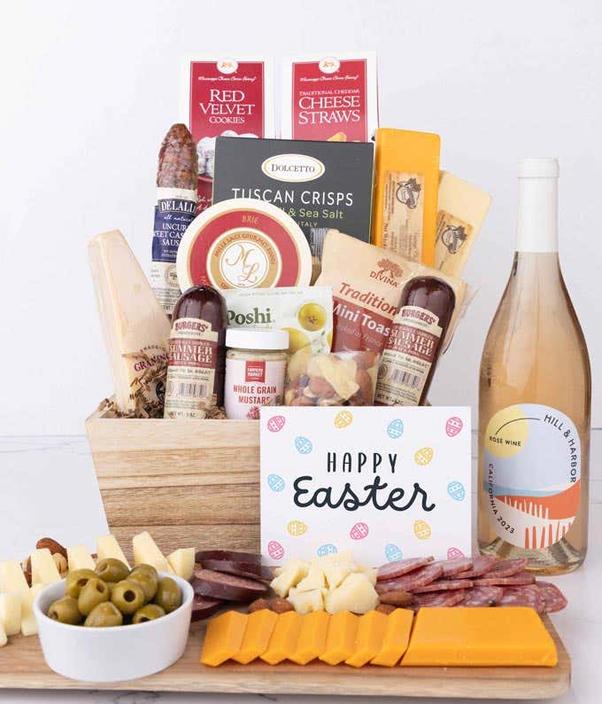 A wooden gift basket filled with summer sausages, 3 cheeses, Tuscan crisps, mini toasts, red velvet cookies, cheese straws, nuts, mustard, and a bottle of wine with an Easter card.