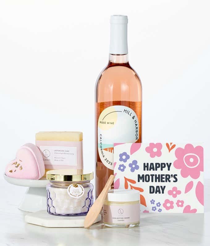 Hill & Harbor California Rosé paired with spa essentials including artisan lavendar soap, a heart-shaped shower steamer, shea butter cream with wooden scoop, and a candle arranged in a clean display with a Mother's Day card.