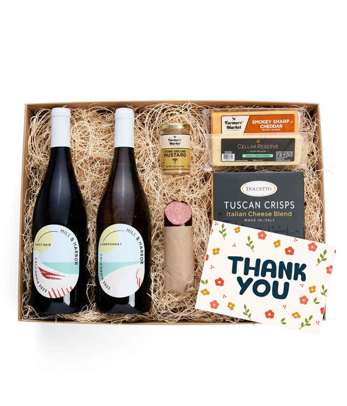 A gift box with two bottles of California wine (Pinot Noir and Chardonnay), two types of cheese, crackers, stone-ground mustard, a summer sausage, and a Thank You message card. 