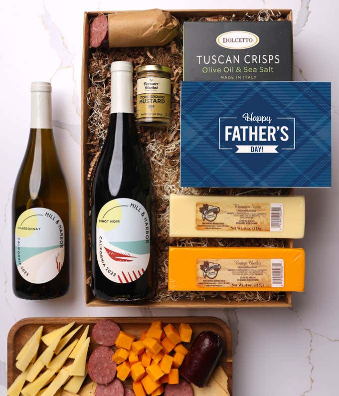 A snack gift box featuring 2 blocks of cheese - cheddar and Swiss, cracker crisps,  summer sausage, mustard, a bottle of red wine and bottle of white wine, finished with a 'Happy Father's Day,' 