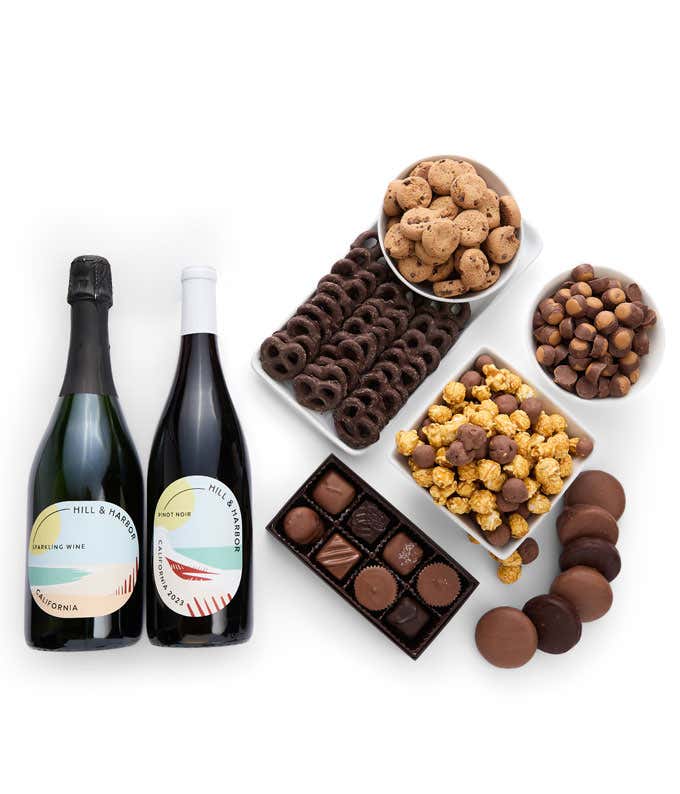 A gift set with 2 bottles of wine - red and sparkling, paired with chocolate pretzels, caramel popcorn, mini cookies, chocolate peanut butter buckeyes, six chocolate-covered Oreos, and a box assorted chocolates.