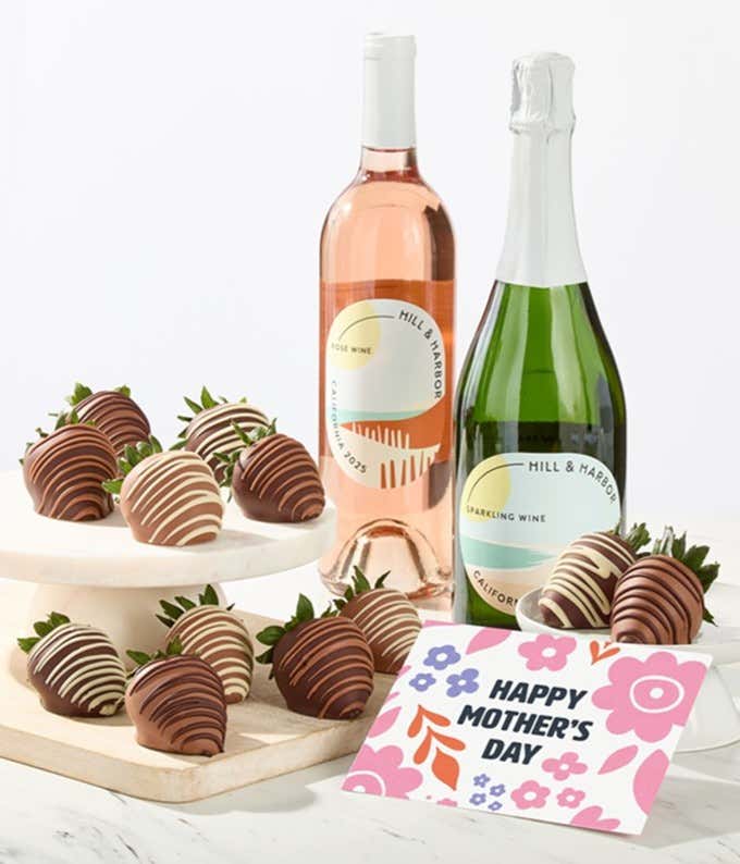 Hill & Harbor rosé and sparkling wine bottles displayed with two glasses and assorted chocolate-covered strawberries on trays, styled with a floral Happy Mother’s Day card for a festive wine gift.