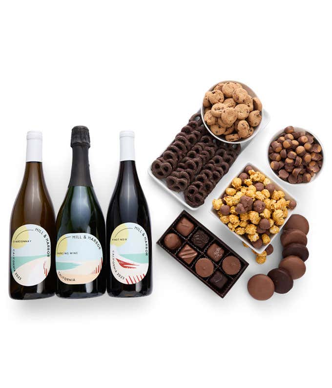 A gift set with 3 bottles of wine - red, white and sparkling, paired with chocolate pretzels, caramel popcorn, mini cookies, chocolate peanut butter buckeyes, six chocolate-covered Oreos, and a box assorted chocolates.