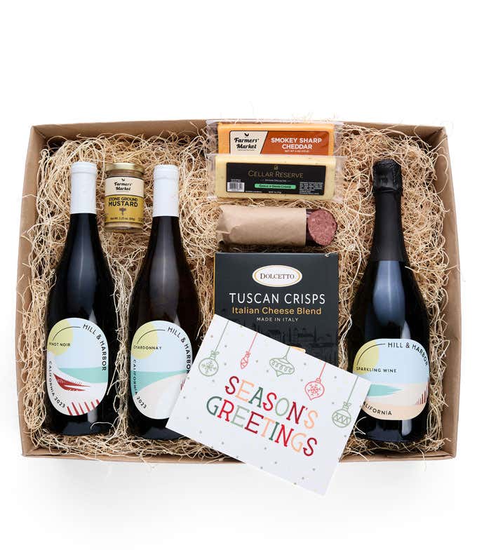 A gift box with three bottles of California wine (red, white, and sparkling), two types of cheese, crackers, stone-ground mustard, a summer sausage, and a festive 'Season's Greetings' card.