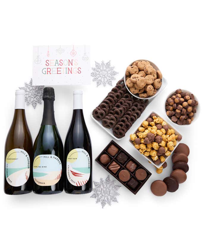 A gift set with 3 bottles of wine - red, white and sparkling, paired with chocolate pretzels, caramel popcorn, mini cookies, chocolate peanut butter buckeyes, six chocolate-covered Oreos, assorted chocolates, and a festive Seasons Greetings card.