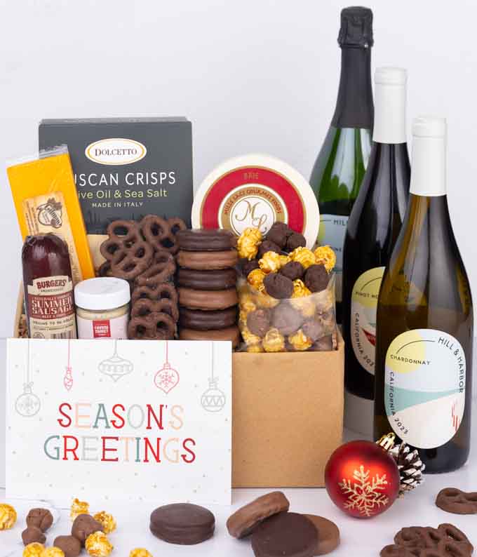 A gift set featuring a trio of California wines - red, white, and sparkling, focaccia crisps, two cheeses, mustard, summer sausage, caramel popcorn, chocolate pretzels, six chocolate-covered Oreos and a Season's Greetings card.