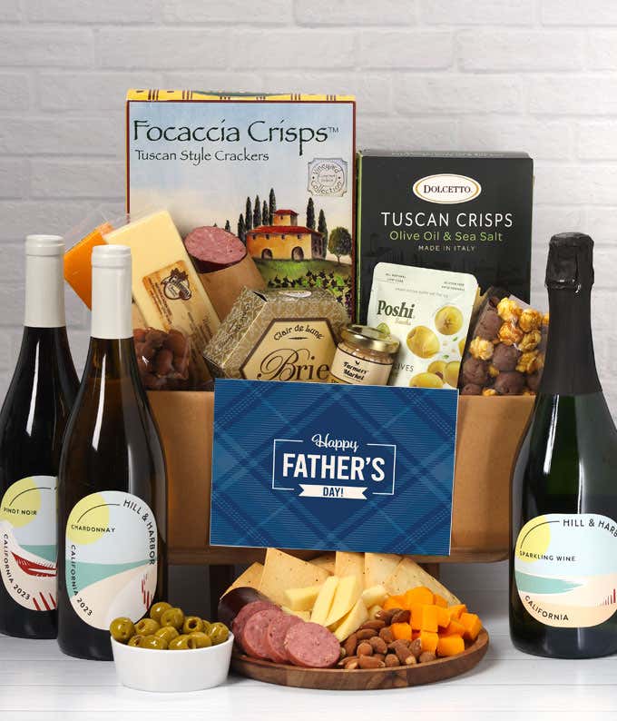 Three bottles of wine with gourmet charcuterie including Tuscan crisps, focaccia crackers, brie, mustard, sausage, 3 cheeses, olives, smoked almonds, and chocolate-covered treats, complete with a 'Happy Father's Day' card.