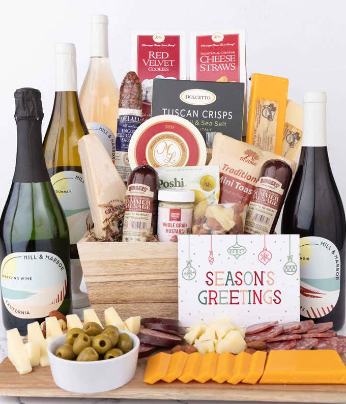 Wooden basket filled with 4 cheeses, 3 sausages, crackers, cookies, nuts, mustard, olives and crisps alongside 4 bottles of wine and Season's Greetings message.