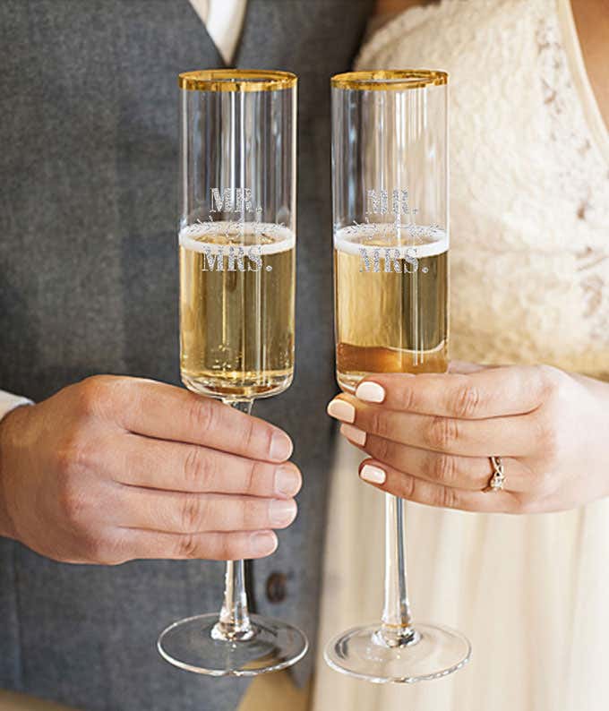 A tall champagne flute with a gold rim is engraved with Mr. & Mrs.