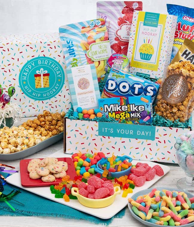 A gift box with a bag of gummy worms, gummy fruit slices, kettle corn, caramel popcorn, Mike &amp; Ike, Sugar cookies, and tootsie pops