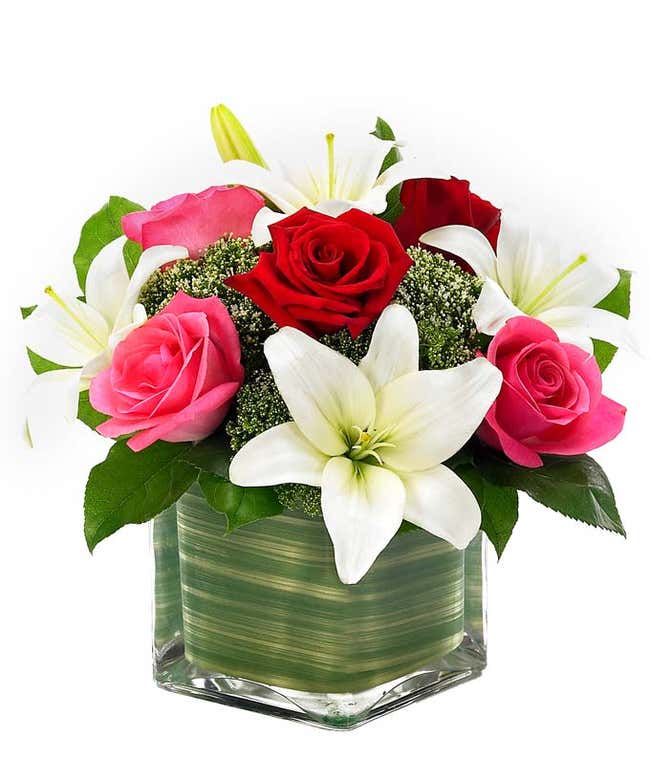 Pink roses, red roses and white lilies in square vase