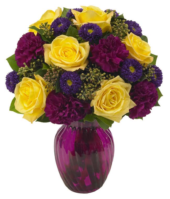 Purple carnations, purple asters and yellow roses in a purple vase