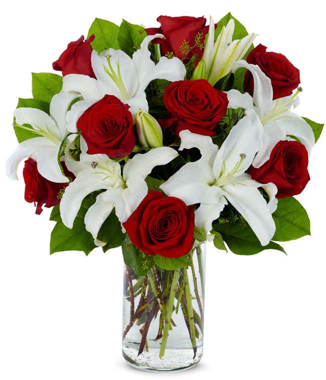 White Stargazer lilies and red roses in a cylinder vase 