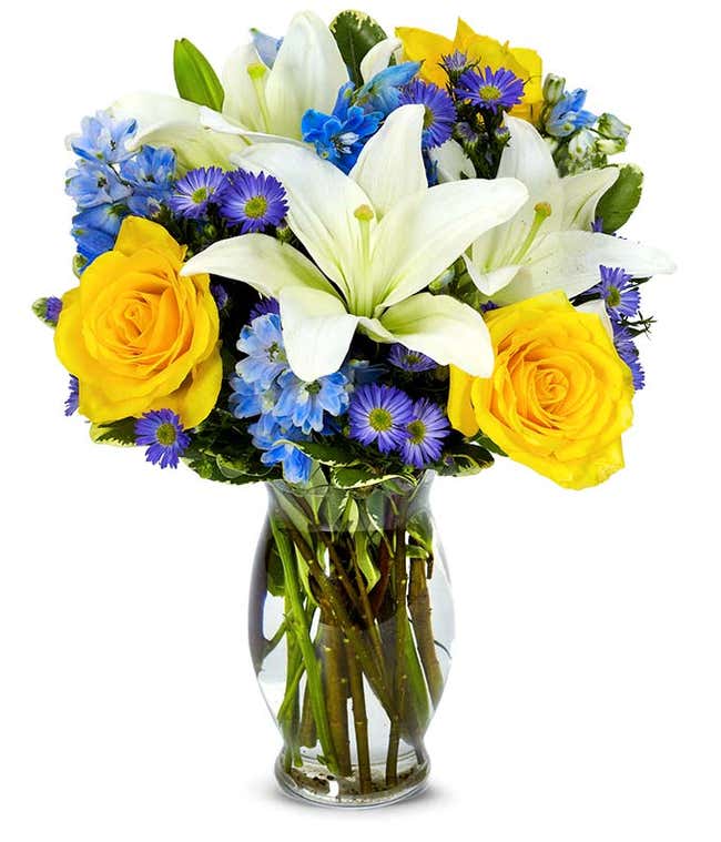 花瓶里装着黄玫瑰、蓝飞燕草和白百合