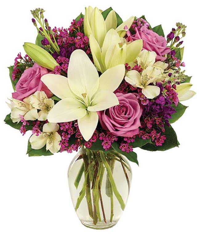 Purple roses and white lilies in a glass vase