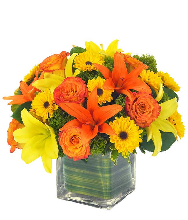 Yellow lilies, orange lilies and orange roses in rectangle vase