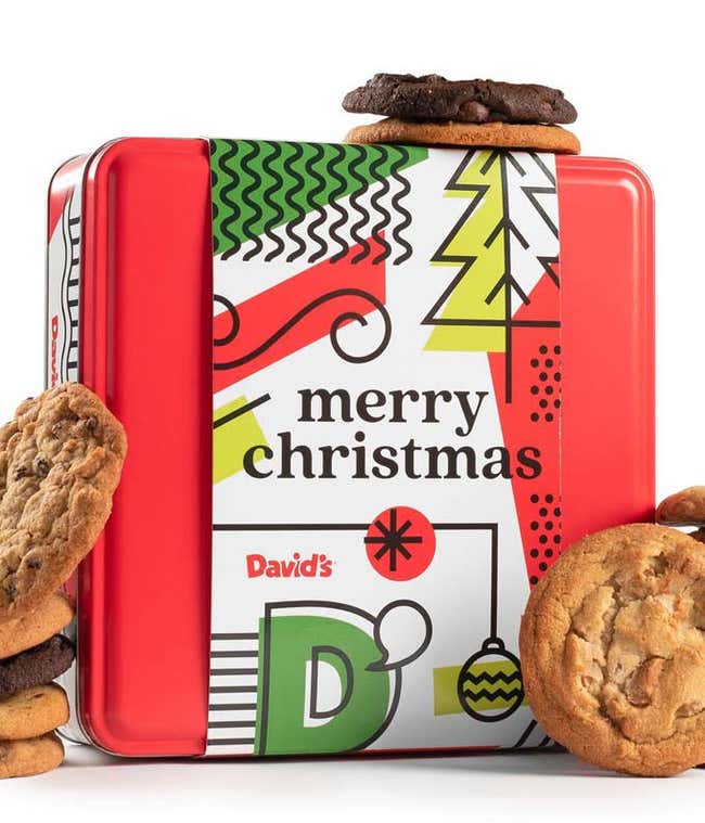 Red tin box with a festive design and Merry Christmas message, filled with assorted cookies, some of which are stacked on and around the box.