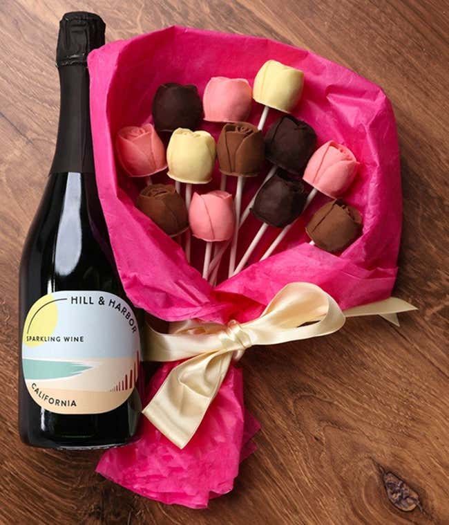 A bouquet of Belgian chocolate roses in milk, dark, and white chocolate, wrapped in pink tissue paper and tied with a cream ribbon, accompanied by a bottle of Hill &amp; Harbor Sparkling Wine