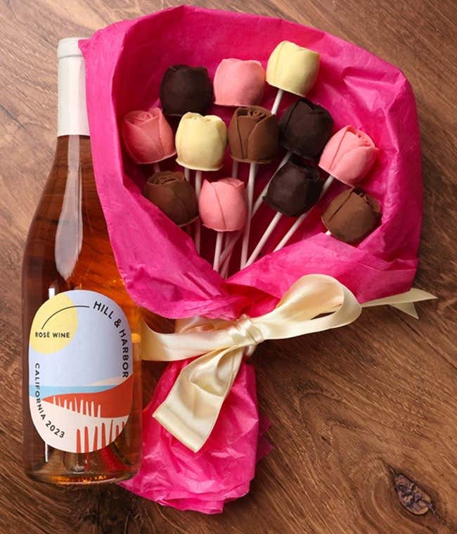 A bouquet of Belgian chocolate roses in milk, dark, and white chocolate, wrapped in pink tissue paper and tied with a cream ribbon, accompanied by a bottle of Hill &amp; Harbor Sparkling Wine