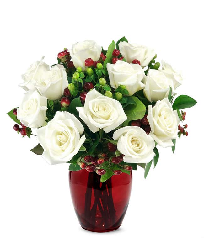 A festive arrangement with white roses, red berries, and green berries. Vase optional