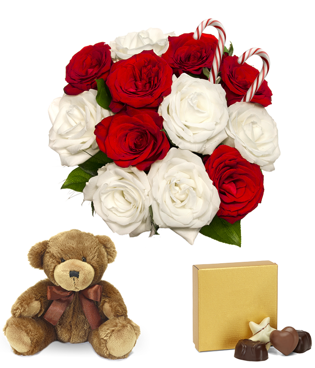 Partial image of A festive arrangement with red roses, white roses, a teddy bear, two candy canes, and a box of chocolates. Vase optional without vase.