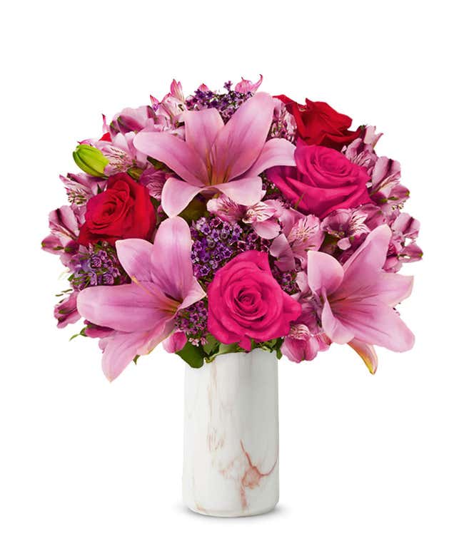A beautiful arrangement featuring pink Asiatic lilies, pink and red roses, and alstroemeria, optionally arranged in a glass vase. This elegant mix offers a lovely and vibrant display