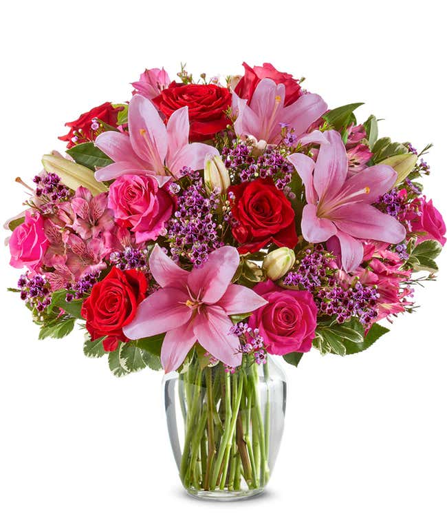A beautiful arrangement featuring pink Asiatic lilies, pink and red roses, and alstroemeria, optionally arranged in a glass vase. This elegant mix offers a lovely and vibrant display