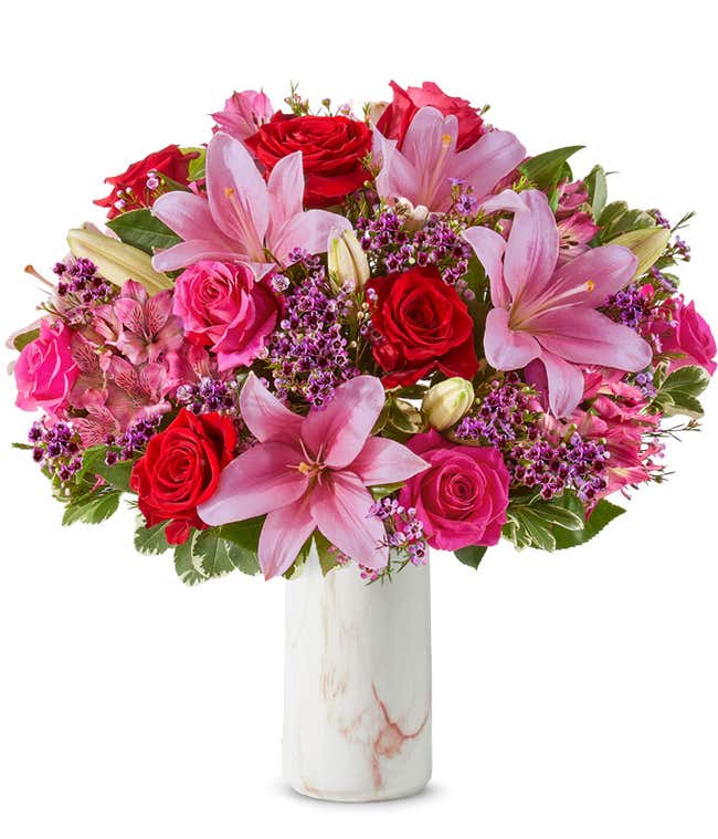 A beautiful arrangement featuring pink Asiatic lilies, pink and red roses, and alstroemeria, optionally arranged in a glass vase. This elegant mix offers a lovely and vibrant display