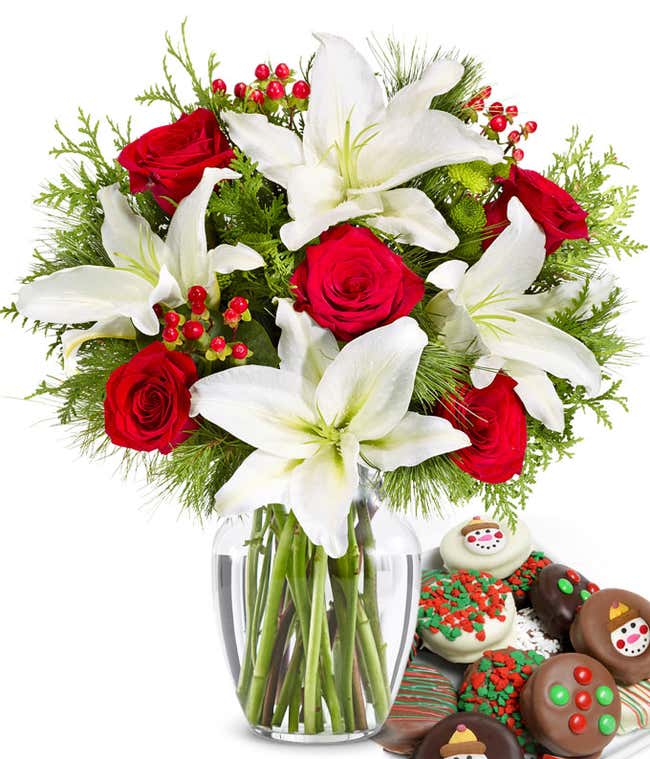 Bouquet of red roses, white lilies, red berries, and  seasonal greens, in a clear vase with one dozen chocolate dipped oreos with candy and snowman toppings