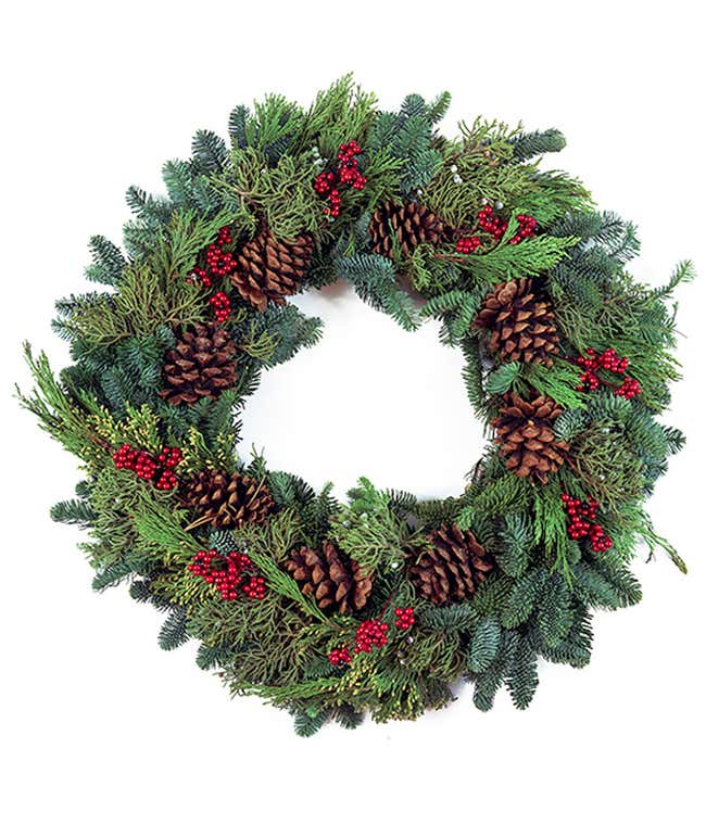 Wreath of mixed seasonal greens decorated with pinecones and red berries