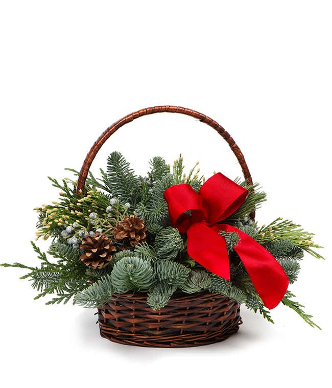Wicker basket full of Christmas greens, pinecones, and a red bow
