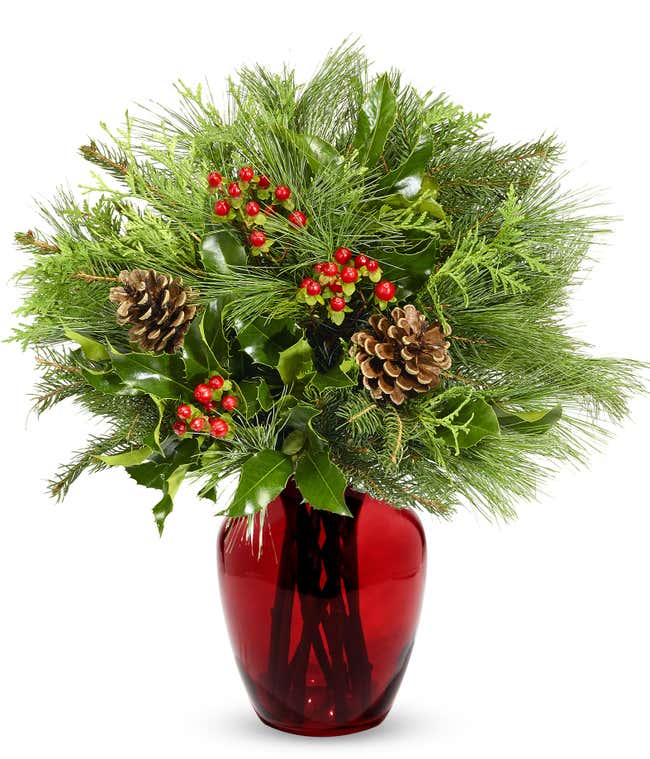 Seasonal greens complemented by decorative pine cones and vibrant red hypericum berries, perfect for a festive holiday arrangement.
