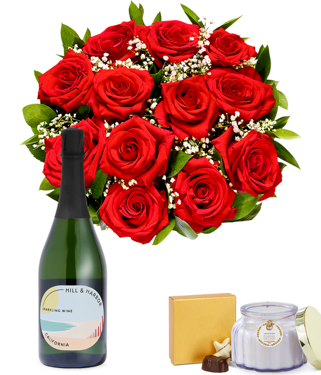 Partial image of One Dozen Red Roses in Clear Glass Vase with box of chocolates, a bottle of sparkling wine, and candle without vase.