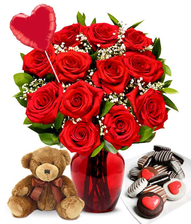 One Dozen Red Roses in a clear glass vase with a red heart mylar balloon, chocolate covered valentine Oreos, and a teddy bear