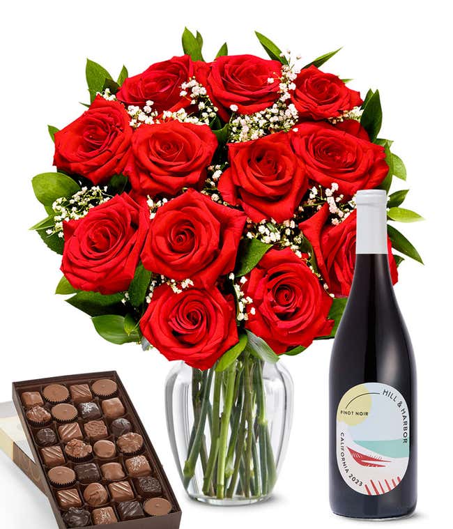 A lush arrangement of a dozen red roses in a clear vase sits beside a bottle of Hill &amp; Harbor Pinot Noir and a 1-pound box of gourmet assorted chocolates.