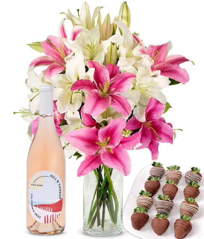 A bouquet of pink and white lilies arranged in a clear glass vase is paired with a bottle of Hill &amp; Harbor Ros&eacute; and 12 chocolate-covered strawberries.