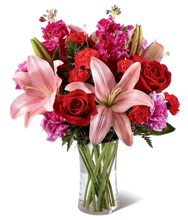 Glass vase with red roses, pink lilies, and red and pink carnations, mini carnations, and stock