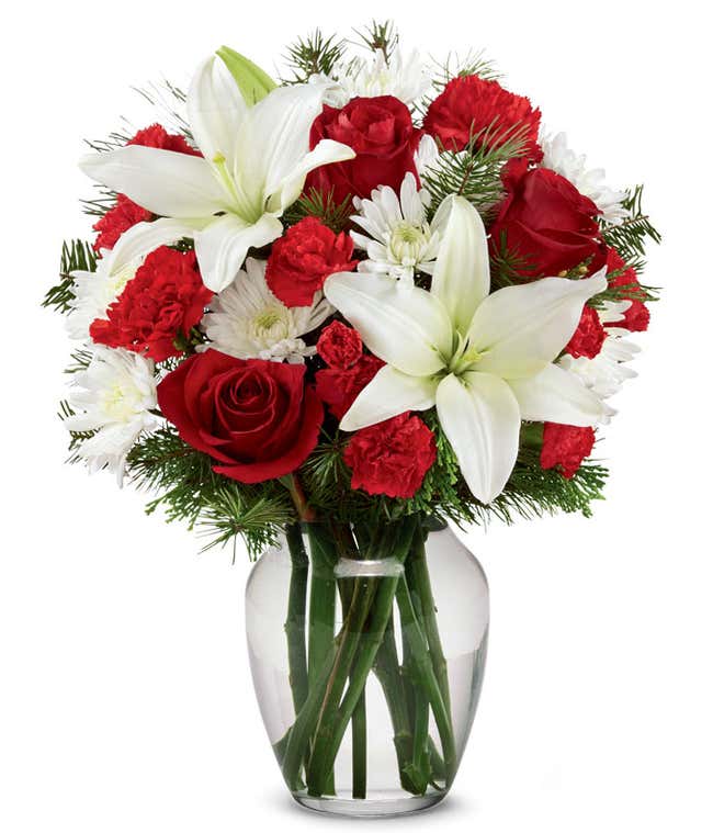 A festive arrangement with red roses, white lilies, red carnations, red mini carnations, and white poms.