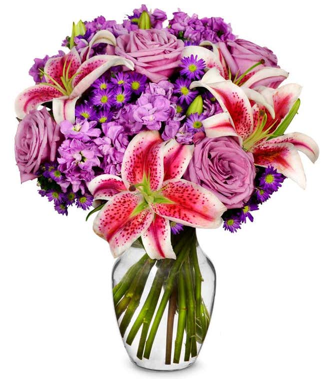 Purple roses, pink stargazer lilies and purple filler flowers in a vase