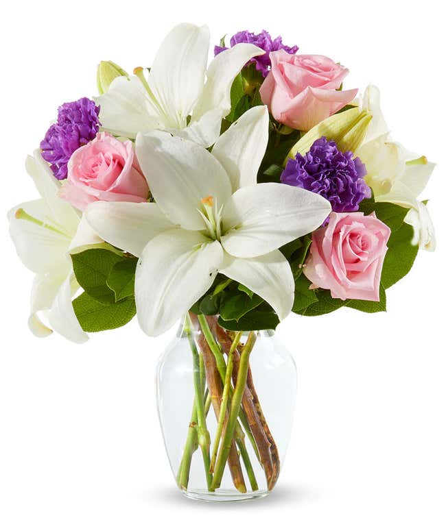 pink roses, purple carnations and white lilies in a clear Vase