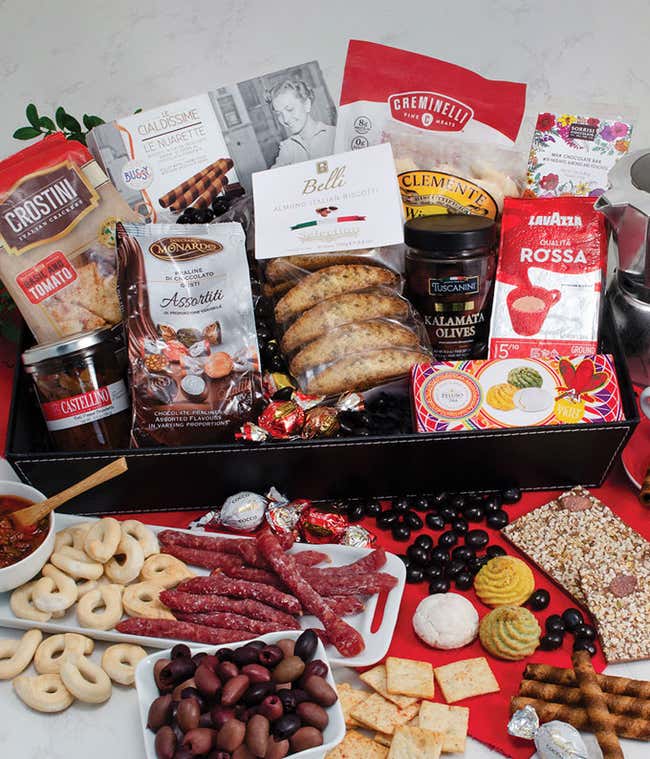 Italian-inspired gift tray featuring salami, Kalamata olives, assorted cookies, biscotti, crostini, crackers, coffee, chocolate, and spreads, arranged with cups of espresso and a moka pot.