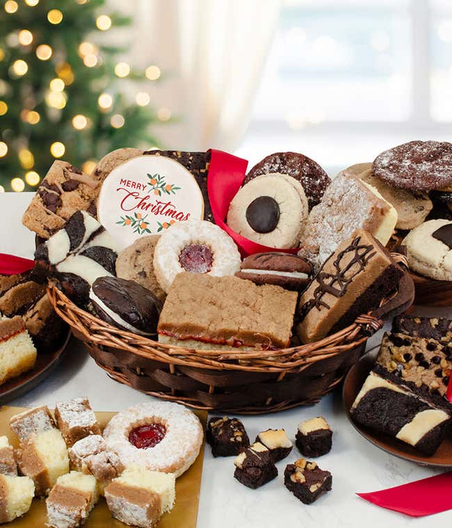 Festive holiday cookie basket filled with assorted treats, including frosted sugar cookies, chocolate chip cookies, brownie bites, and layered bars, with a red coffee mug nearby.