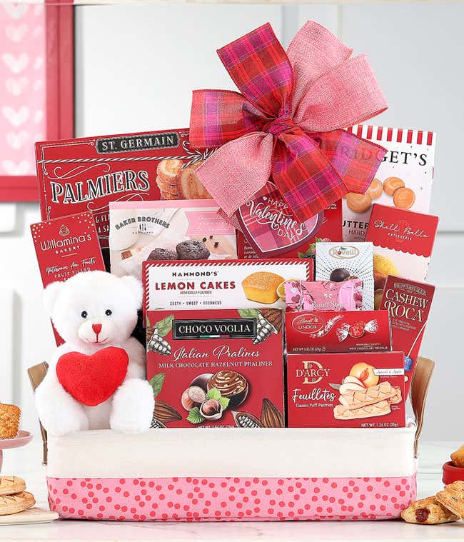 Red Gift Basket with packages of lemon cakes, Ghirardelli Chocolate Squares, and more with a red bow with hearts, and a white teddy bear holding a red heart