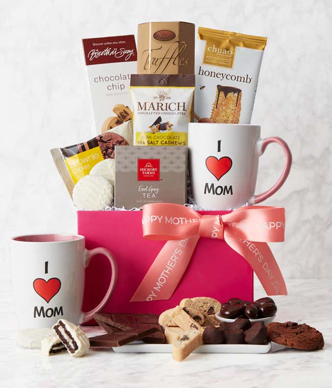 A Mother's Day gift basket containing Chocolate Chip Biscotti, Brownie Cookies, Mom Mug, Honeycomb Chocolate Bar, French Truffles, White Chocolate Covered Sandwich Cookies, Dark Chocolate Sea Salt Cashews, and Earl Grey Tea, beautifully presented with a p