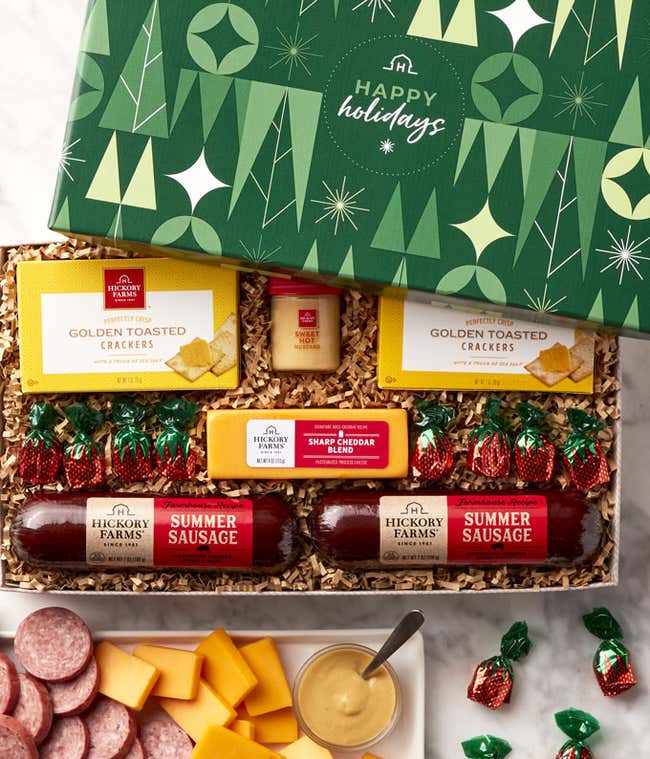 Holiday gift box with Hickory Farms summer sausages, golden toasted crackers, smoked cheddar blend, sweet hot mustard, and assorted chocolates, displayed with sliced sausage, cheese, crackers, and mustard on a serving tray.