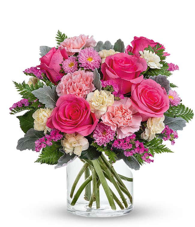 Pink roses and carnations arranged in a clear glass cylinder vase 