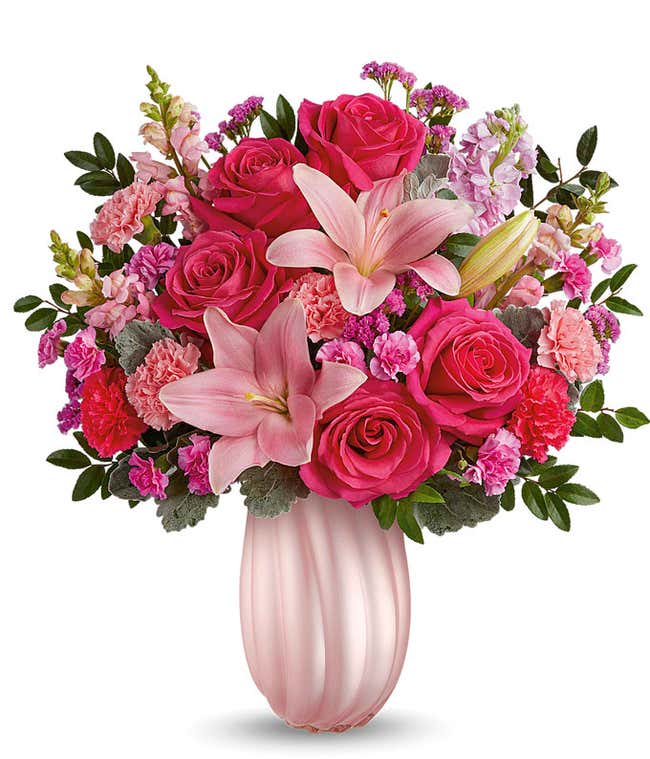 Image of a Mother's Day arrangement featuring Hot Pink Roses, Pink Asiatic Lilies, Light Pink Carnations, Hot Pink Carnations, Miniature Hot Pink Carnations, Pink Snapdragons, Light Pink Stock, Raspberry Sinuata Statice, all beautifully presented in a kee