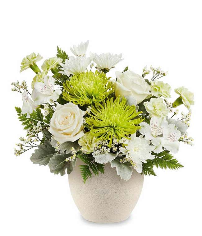 White Roses, White Alstroemeria, Green Carnations, Mini Green Carnations, White Cushion Poms, Green Fuji Mums, and floral greenery in a modern stone bowl vase
